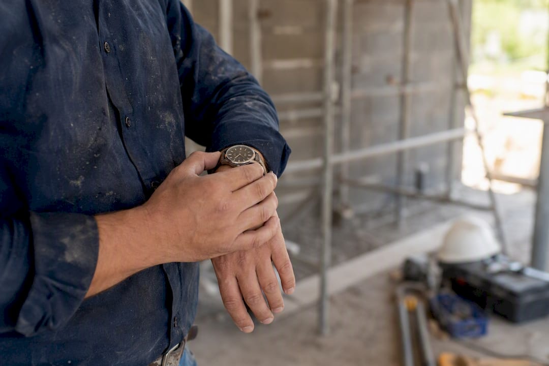 Ein Bauleiter wirft einen Blick auf seine Armbanduhr und stellt sie direkt auf der Baustelle ein.