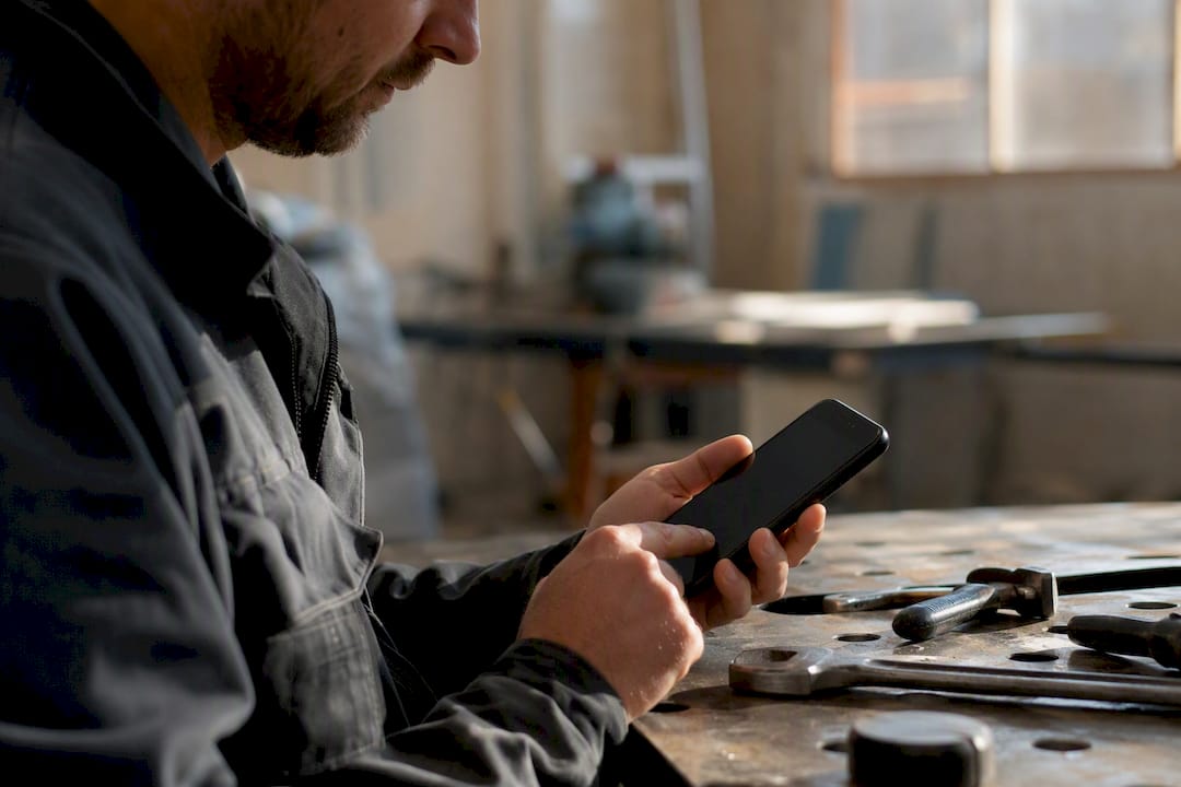 Handwerker nutzt Smartphone in der Werkstatt